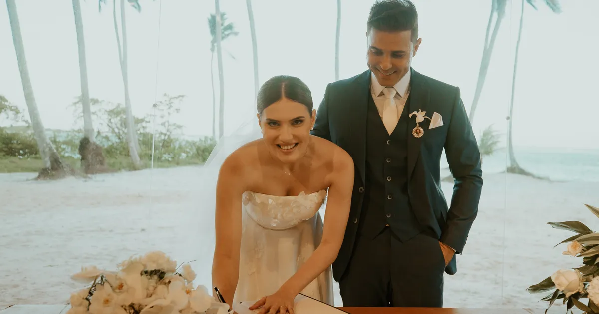Thalita assina o livro na cerimônia do casamento dos Medinas, com o Leonardo ao lado, diante da praia